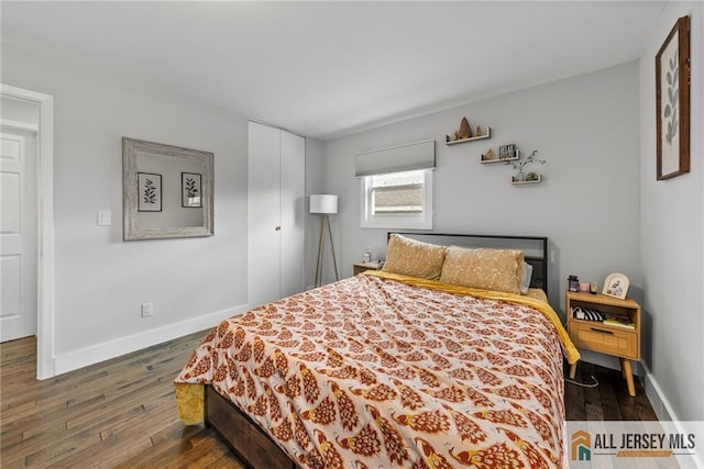 bedroom featuring dark wood-style flooring, a closet, and baseboards