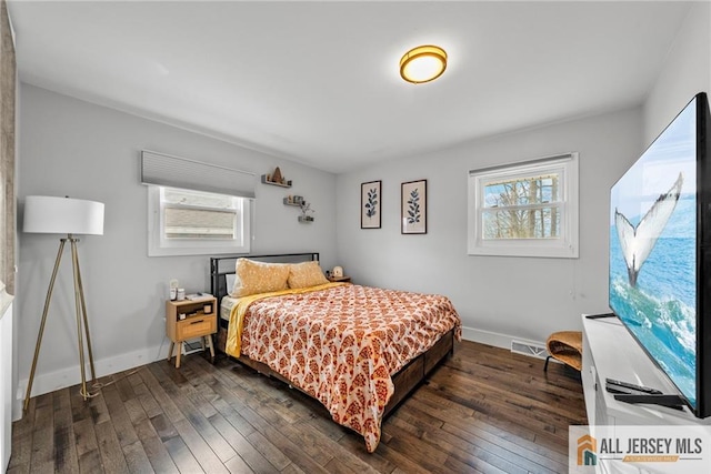 bedroom with multiple windows, baseboards, and dark wood-type flooring