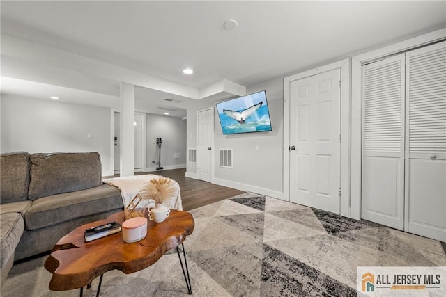 living room featuring baseboards, visible vents, wood finished floors, and recessed lighting