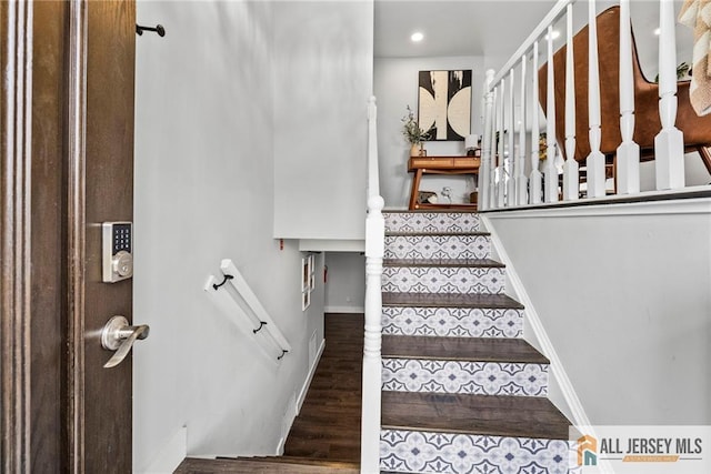 staircase featuring wood finished floors and baseboards