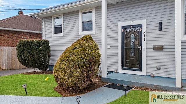 view of exterior entry featuring a yard and fence