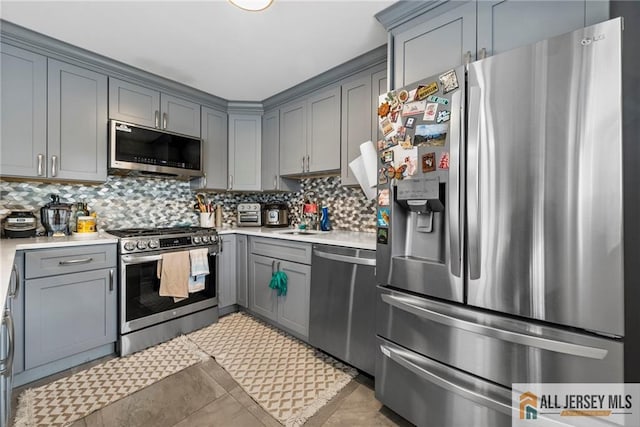 kitchen featuring light countertops, appliances with stainless steel finishes, backsplash, and gray cabinetry