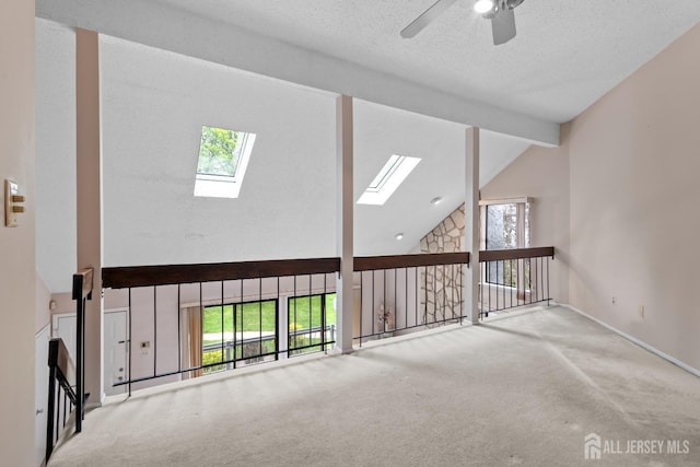 additional living space with a skylight, high vaulted ceiling, ceiling fan, beam ceiling, and carpet floors