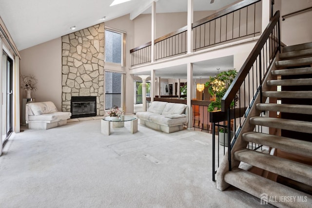 carpeted living room with stairs, high vaulted ceiling, a fireplace, and beam ceiling