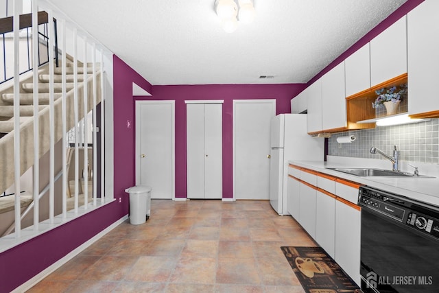 kitchen with black dishwasher, a sink, freestanding refrigerator, white cabinets, and decorative backsplash