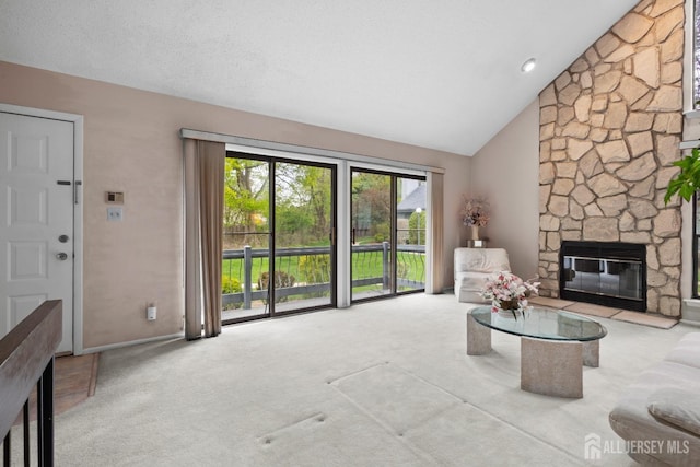 carpeted living area with a stone fireplace, high vaulted ceiling, and baseboards