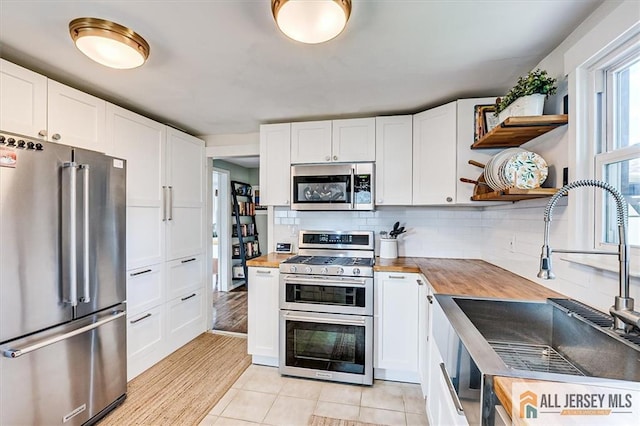121 E Cliff Rd, Colonia, NJ 07067 - kitchen with appliances with stainless steel finishes, open shelves, wooden counters, white cabinets, and decorative backsplash