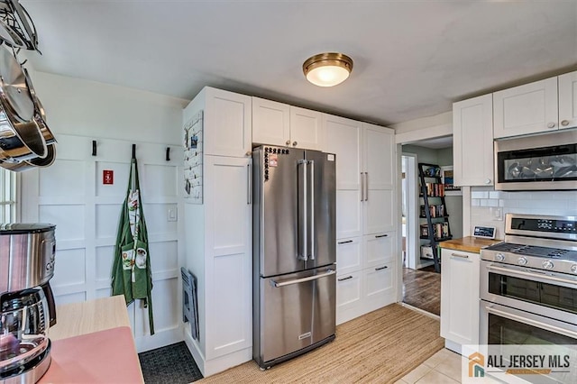 121 E Cliff Rd, Colonia, NJ 07067 - kitchen featuring stainless steel appliances, white cabinets, tasteful backsplash, and light tile patterned flooring