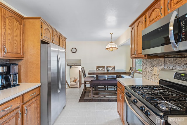 1208 Omaha Rd, North Brunswick, NJ 08902 - kitchen featuring stainless steel appliances, backsplash, light countertops, brown cabinets, and pendant lighting