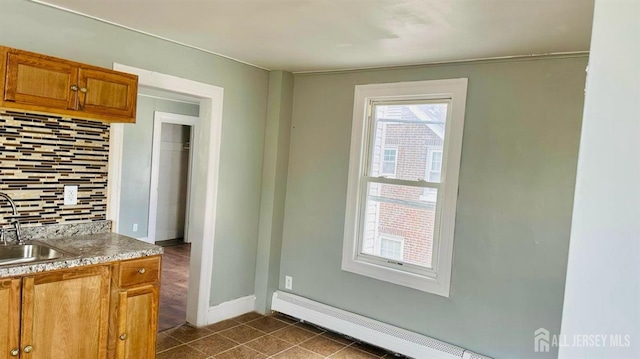 interior space featuring dark tile patterned floors, indoor wet bar, baseboards, a baseboard radiator, and a sink