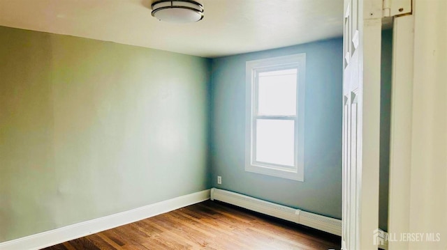 spare room featuring dark wood-type flooring, a baseboard radiator, baseboards, and a wealth of natural light