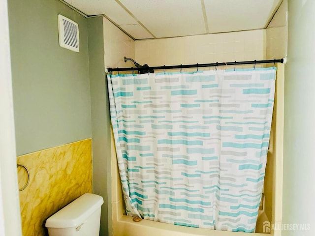 bathroom featuring toilet, shower / tub combo with curtain, and visible vents