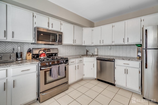 kitchen featuring white cabinetry, backsplash, stainless steel appliances, and light tile patterned flooring