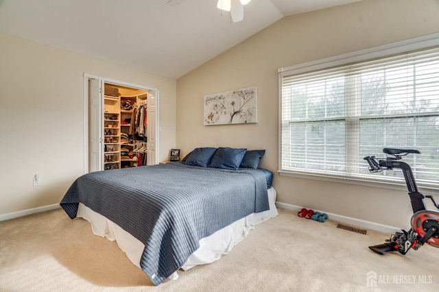 carpeted bedroom with vaulted ceiling, a walk in closet, ceiling fan, and a closet