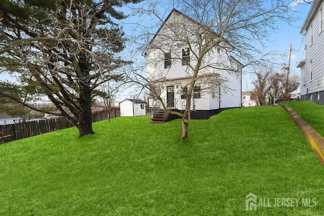 view of yard featuring a shed, fence, and an outbuilding