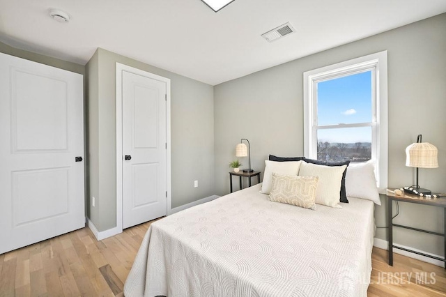 bedroom with light wood finished floors, baseboards, and visible vents