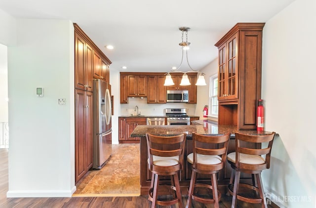 1682 Taylor Dr, North Brunswick, NJ 08902 - kitchen featuring appliances with stainless steel finishes, a peninsula, recessed lighting, brown cabinets, and glass insert cabinets
