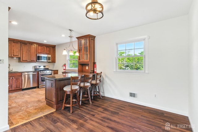 1682 Taylor Dr, North Brunswick, NJ 08902 - kitchen featuring stainless steel appliances, a breakfast bar, a peninsula, wood finished floors, and glass insert cabinets