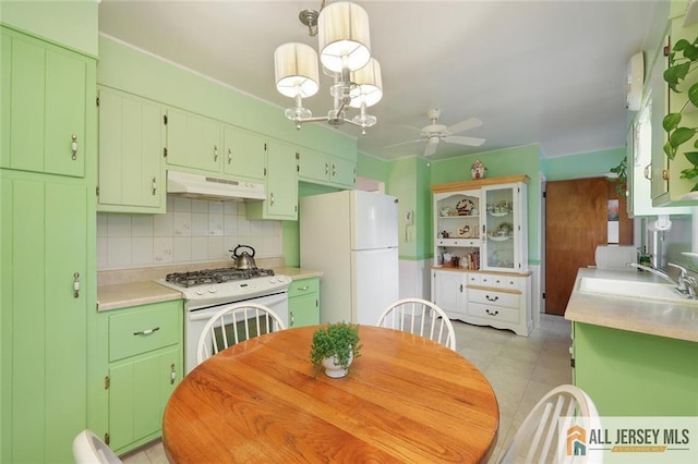 kitchen with white appliances, under cabinet range hood, a sink, a ceiling fan, and light countertops