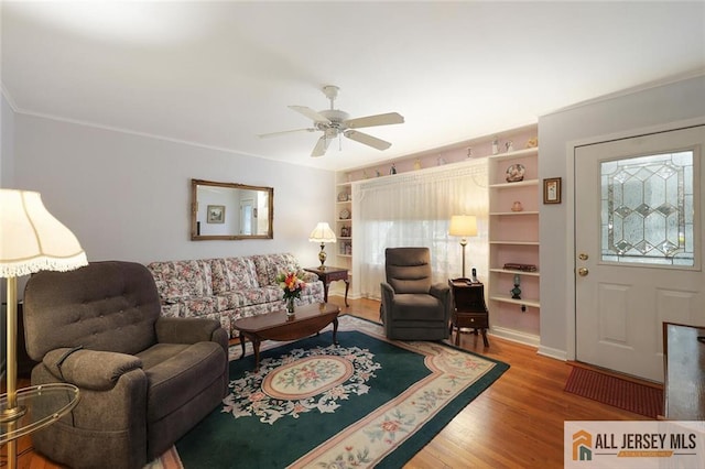 living room with plenty of natural light, wood finished floors, a ceiling fan, and crown molding