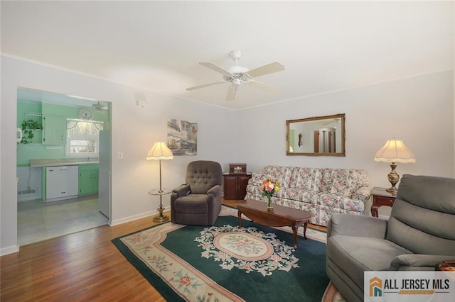 living room featuring ceiling fan, baseboards, wood finished floors, and ornamental molding