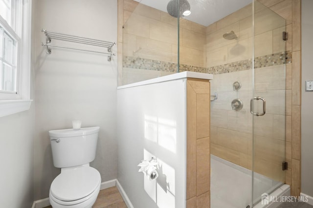 full bath featuring toilet, baseboards, and a stall shower