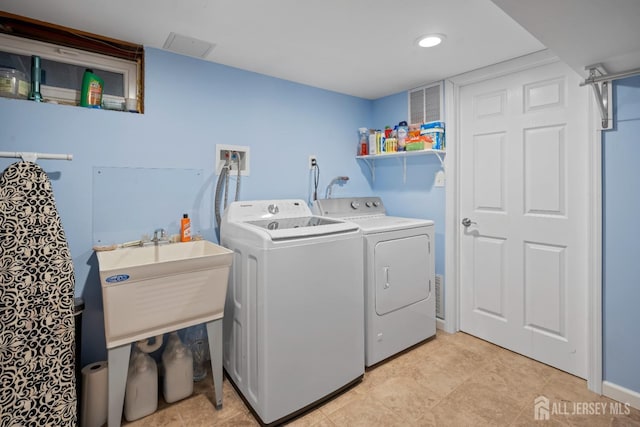 washroom with a sink, baseboards, laundry area, and washer and dryer