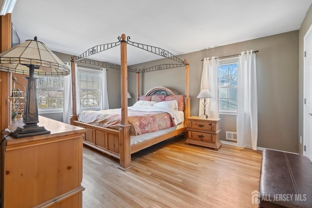 bedroom featuring visible vents, light wood-style flooring, and baseboards