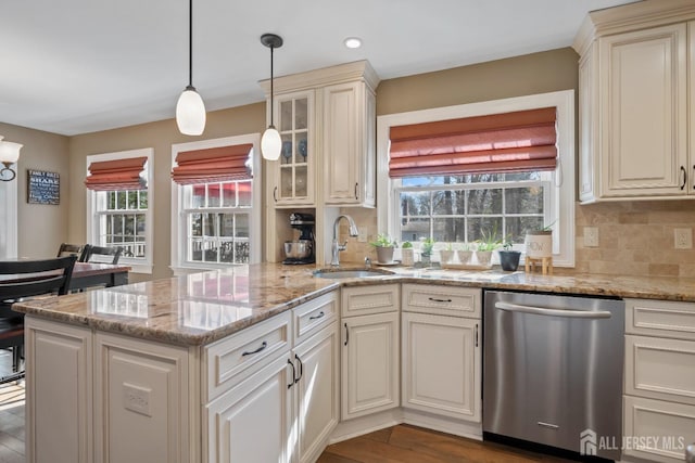 kitchen featuring stainless steel dishwasher, a sink, a peninsula, and cream cabinets