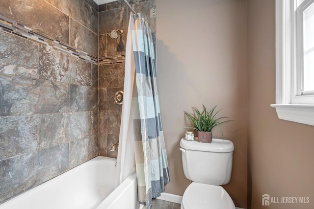 bathroom with toilet, baseboards, and shower / tub combo