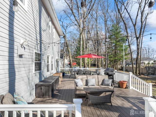wooden terrace featuring area for grilling, outdoor lounge area, outdoor dining area, and a trampoline