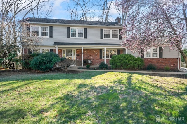traditional home with brick siding, a front lawn, and a chimney