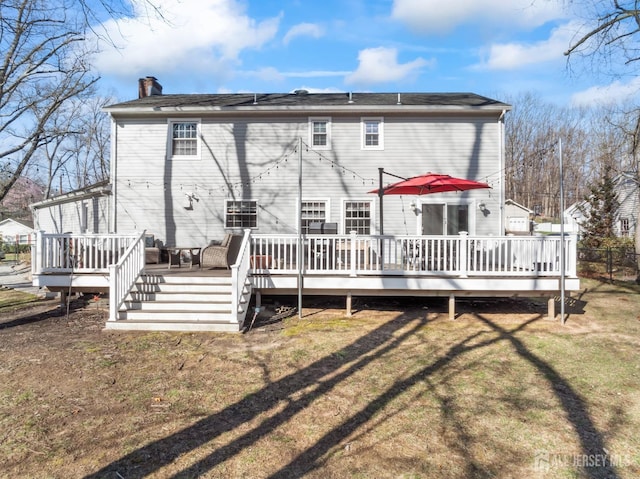 rear view of property featuring a lawn, a wooden deck, and a chimney