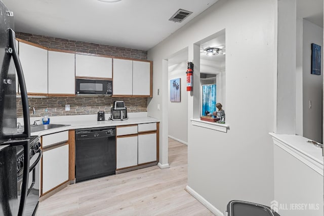 907 Meadow Ct, Helmetta, NJ 08828 - kitchen with light countertops, black appliances, light wood-style floors, white cabinets, and tasteful backsplash