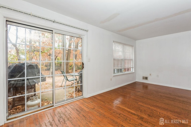 spare room with visible vents, baseboards, and hardwood / wood-style flooring