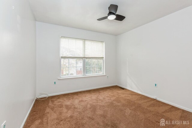 empty room with visible vents, carpet flooring, a ceiling fan, and baseboards