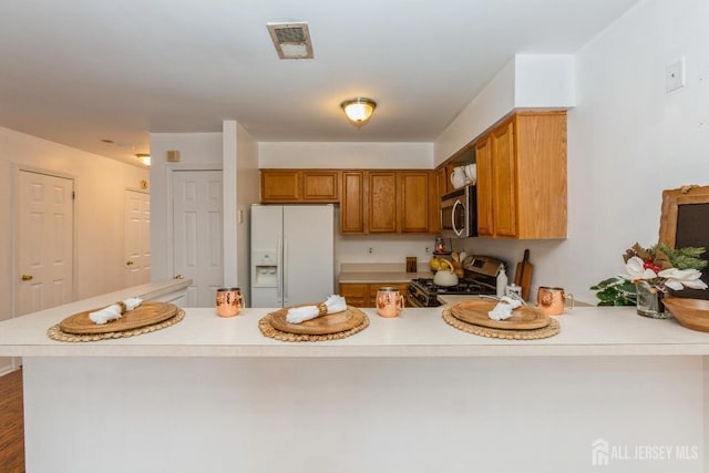 kitchen with a peninsula, light countertops, visible vents, and appliances with stainless steel finishes