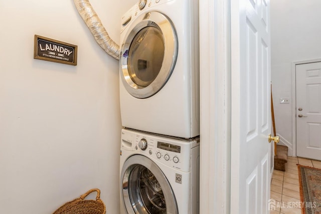 laundry room featuring stacked washer and dryer and light tile patterned floors