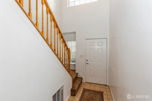 foyer featuring stairway, light tile patterned floors, visible vents, and a wealth of natural light