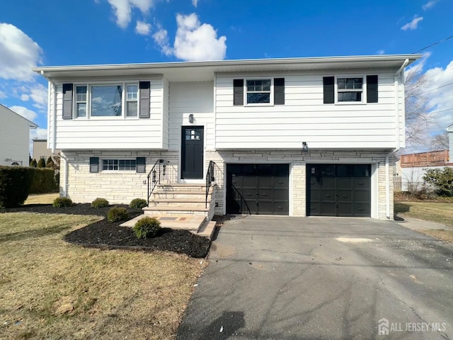 split foyer home featuring brick siding, driveway, and an attached garage