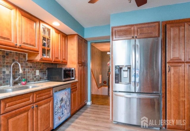 kitchen featuring ceiling fan, sink, stainless steel appliances, backsplash, and light wood-type flooring