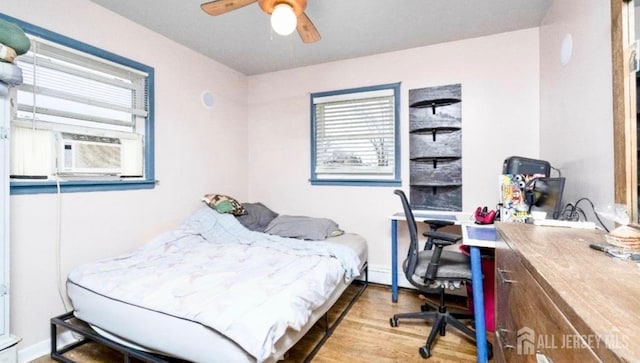 bedroom featuring a ceiling fan, cooling unit, and wood finished floors