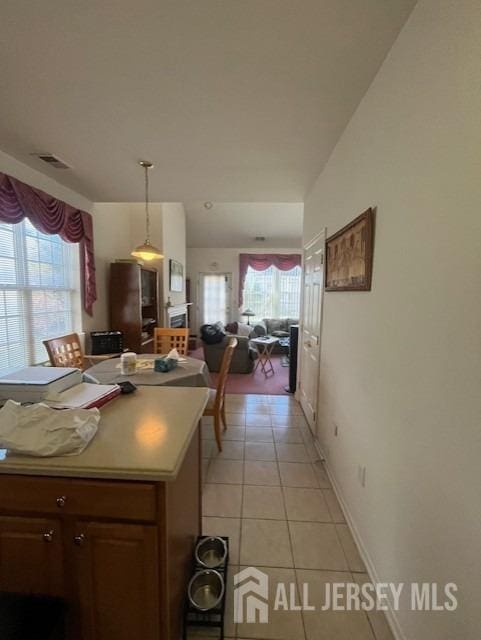 kitchen with hanging light fixtures, a wealth of natural light, and light tile patterned flooring