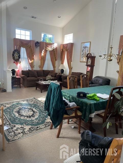 living area with high vaulted ceiling, carpet flooring, and visible vents