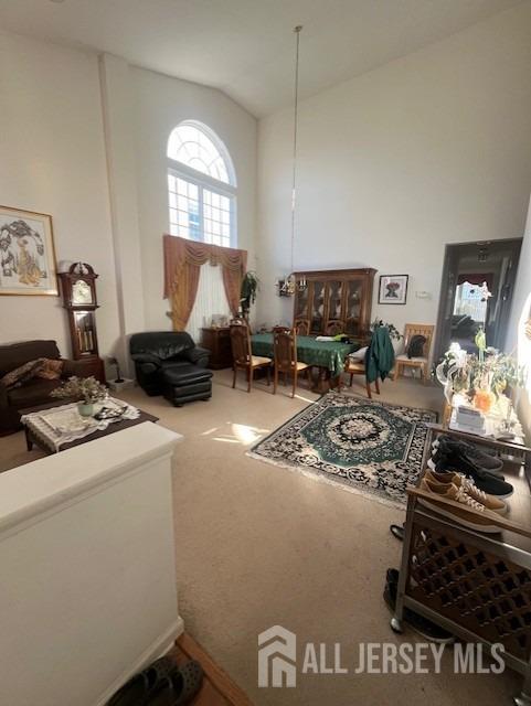 carpeted living room featuring high vaulted ceiling