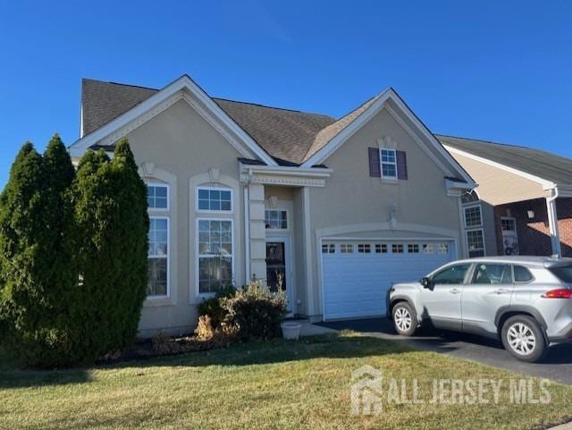 view of front of house featuring a garage, a front lawn, and stucco siding