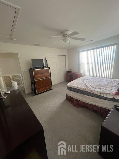 bedroom with a closet, visible vents, attic access, a ceiling fan, and light carpet