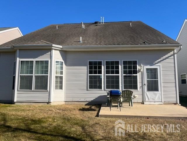 rear view of property featuring a patio area, a lawn, and roof with shingles