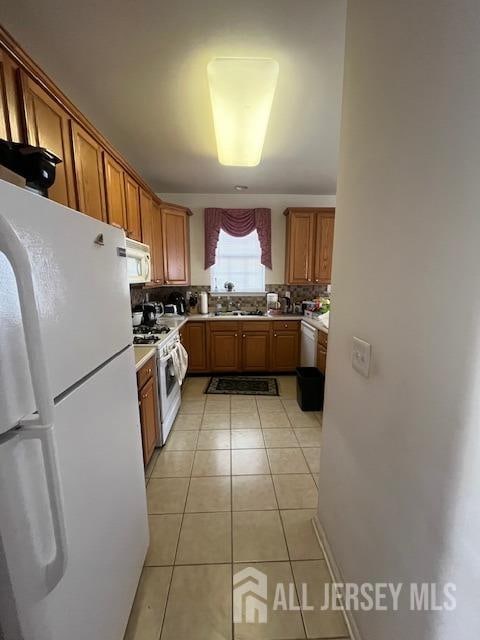 kitchen with decorative backsplash, light tile patterned floors, and white appliances