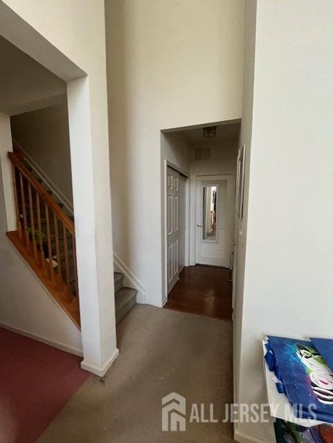 hall with stairs, a high ceiling, carpet flooring, and baseboards